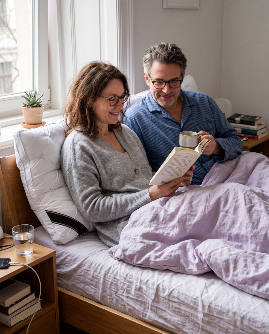 Paar liest im Bett an Wolkenkissen gelehnt